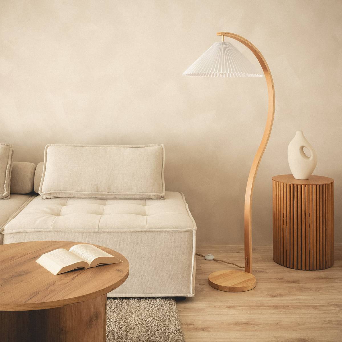 Lichte bank met houten booglamp en ronde salontafel in een warm, naturel interieur